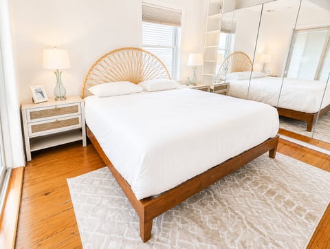 Bright, serene bedroom with mirrored closets and stylish woven headboard