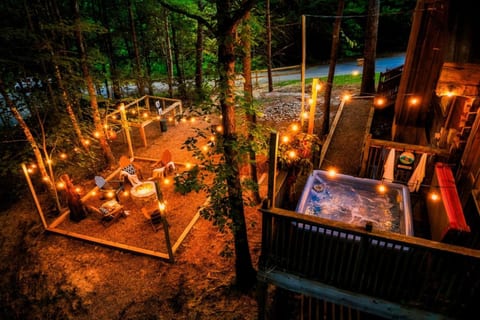 Stunning aerial view of Cubby Bear Den at night featuring private hot tub, wraparound deck, and string lights nestled in the Smoky Mountains
