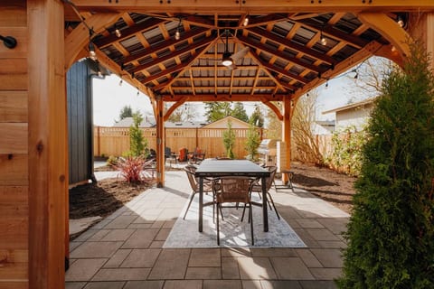 Covered pavilion dining, string lights, ceiling fan, and seating for six under timber beams