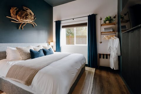 The Tide Room: king bed, driftwood crab, deep blue velvet curtains, and cozy robes waiting.