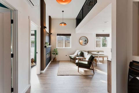 Soaring ceilings, loft above, fireplace wall, and bedroom peek. The whole space breathes