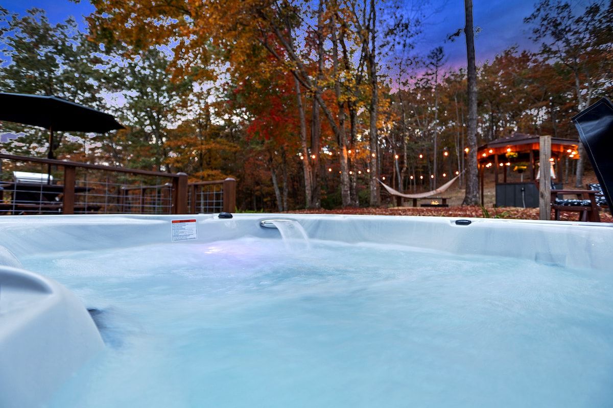 Private hot tub with wooded views, string lights, hammock, and a peaceful outdoor retreat just steps away.