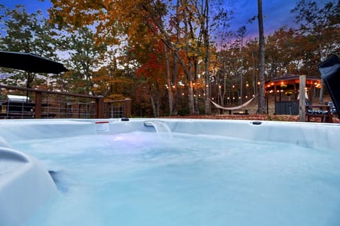 Private hot tub with wooded views, string lights, hammock, and a peaceful outdoor retreat just steps away.