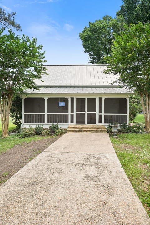 Charming cottage with screened porch, metal roof, and leafy curb appeal