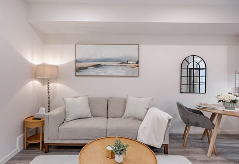 Bright, modern living area with a cozy sofa, soft lighting, stylish décor, and a dining space. Clean neutral tones and contemporary finishes create a warm, relaxing atmosphere perfect for unwinding.