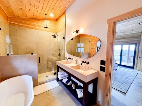 Spa-inspired full bathroom is private ensuite to the primary king bedroom. It includes a double vanity, standalone soaking tub, and oversized shower with double heads. 
