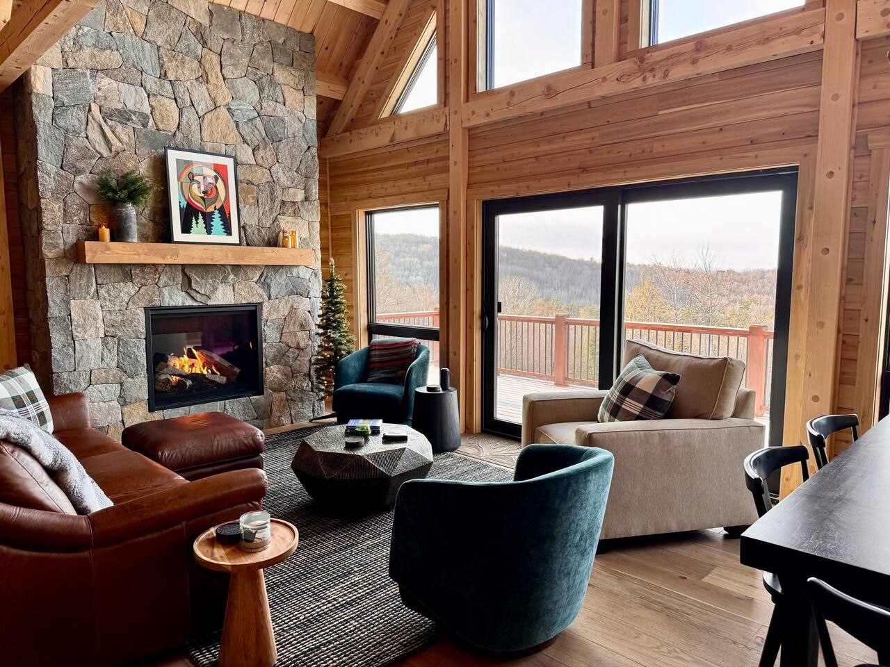 Main level great room offers a soaring custom fireplace, window wall with views over the valley, comfortable seating, coffee table, dining table for up to 8, sliding door out to oversized deck.