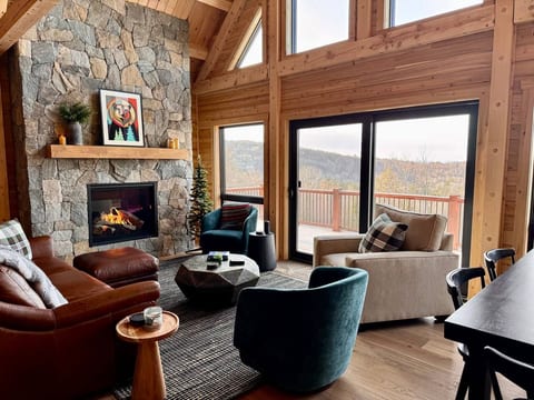Main level great room offers a soaring custom fireplace, window wall with views over the valley, comfortable seating, coffee table, dining table for up to 8, sliding door out to oversized deck.