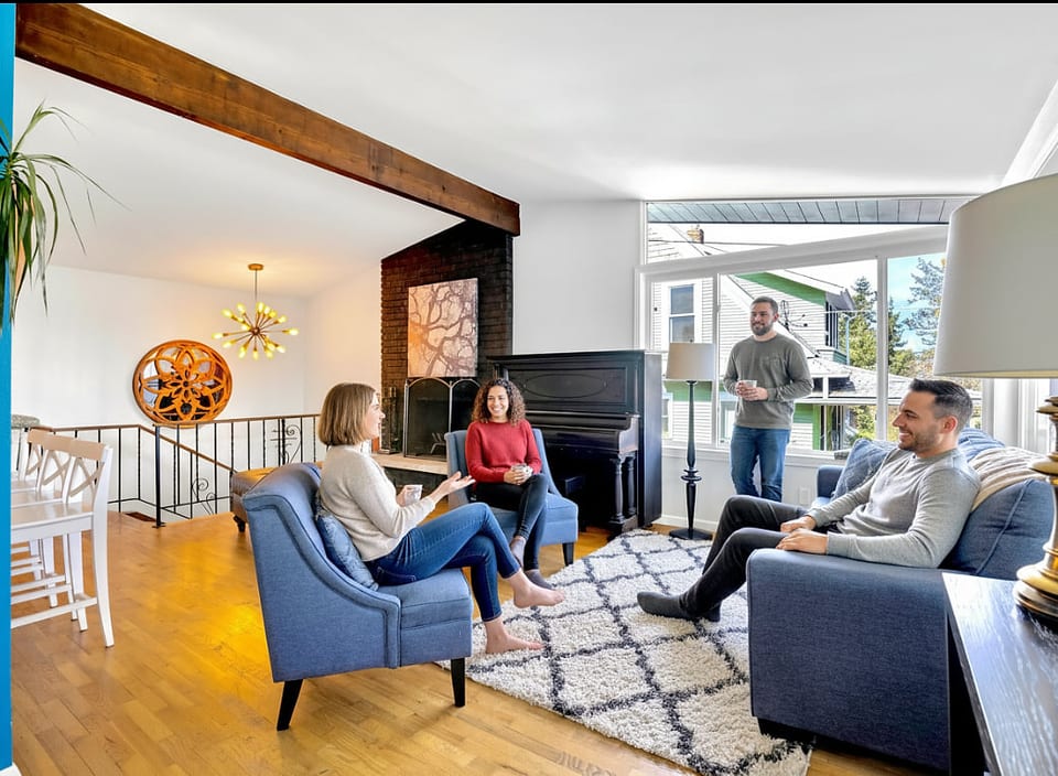 Bright, cozy living room with fireplace, piano, and sunny seating area