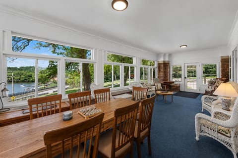 Sunny enclosed porch with water views, dining space, and cozy seating