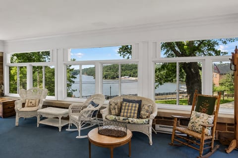 Sunny enclosed porch with cozy seating and serene water views