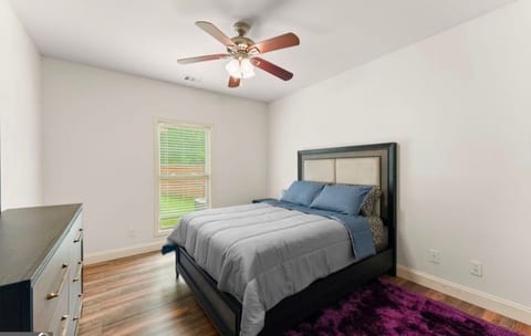 Bright, modern bedroom with cozy bed, natural light, and ceiling fan