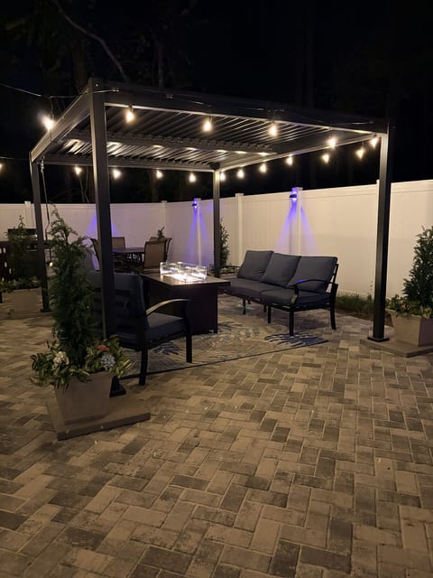 Cozy pergola patio with fire table, string lights, and private fenced yard