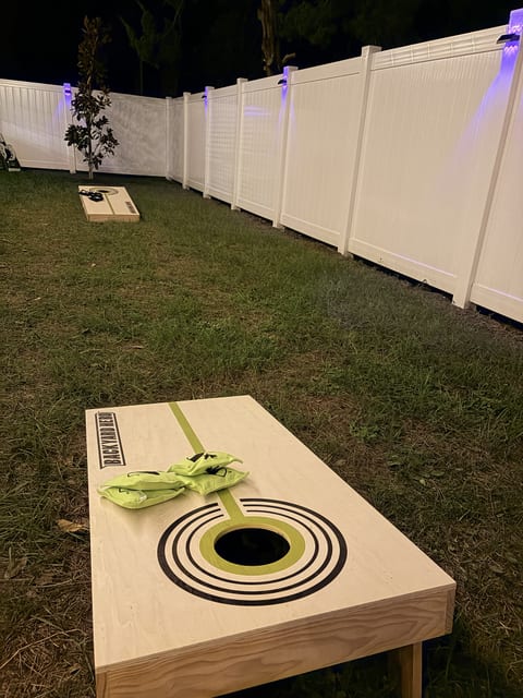 Private fenced backyard with lit lawn games for fun evening hangouts