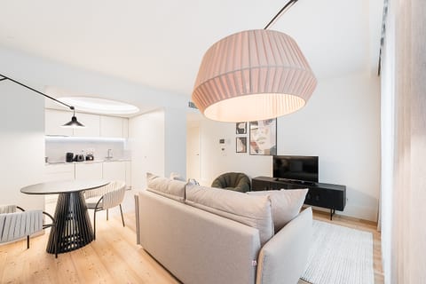 Bright open-plan lounge with sleek kitchen, TV, and cozy seating