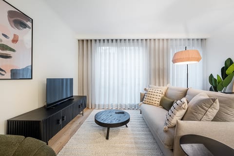Bright modern lounge with plush sofa, smart TV, and cozy chic decor.