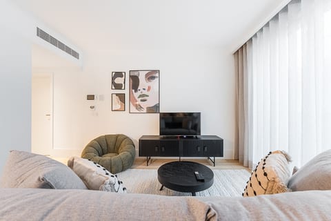 Sunlit modern lounge with smart TV, chic art, and cozy designer seating