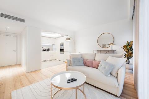 Sunlit, minimalist lounge with sleek kitchen and cozy pastel accents