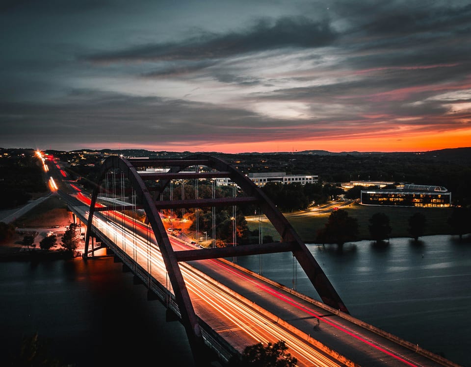 Sunset over arch bridge and river—near parks, trails, and dining.