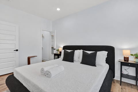 Serene king bedroom with plush bedding, warm lamps, and closet/bath access