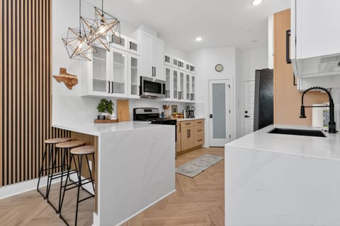 Sleek chef’s kitchen with quartz, bar seating & herringbone floors