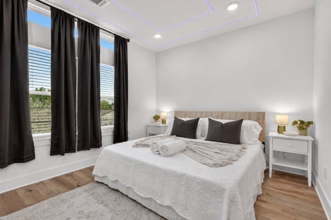 Bright modern bedroom with king bed, LED ceiling glow, and big windows.