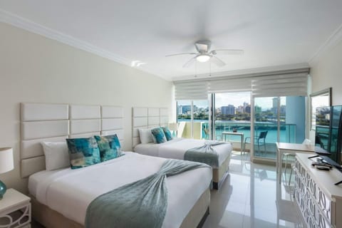 modern twin bedroom with balcony overlooking the water and city skyline