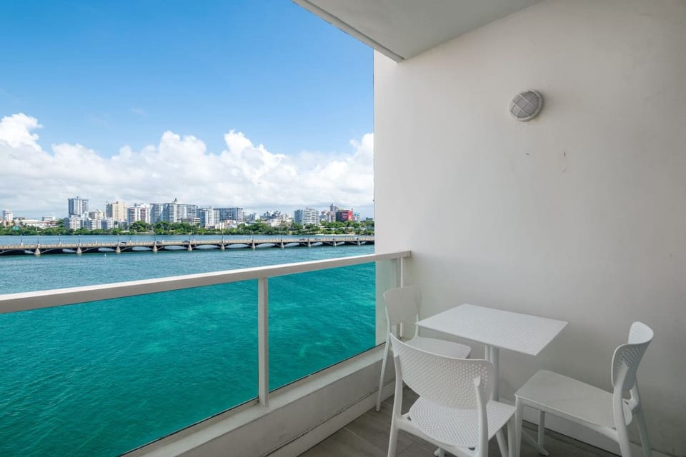 Private balcony with seating area and stunning waterfront views under clear blue skies