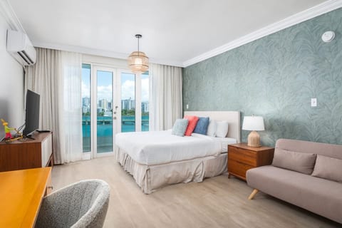 Modern bedroom with king bed, stylish accent wall, and private balcony overlooking the water