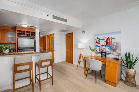 Open-concept living space with kitchenette, dining bar, and dedicated workspace