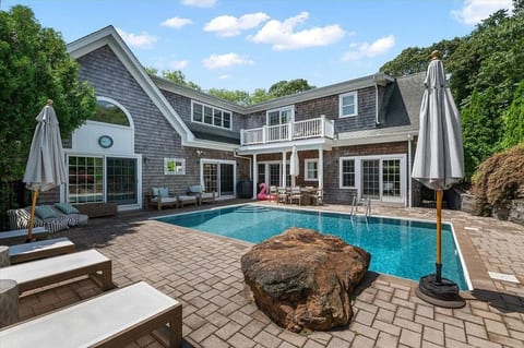 The heated saltwater pool sits at the heart of the property, surrounded by a spacious patio with dining, lounge seating, and direct access from the main living level.