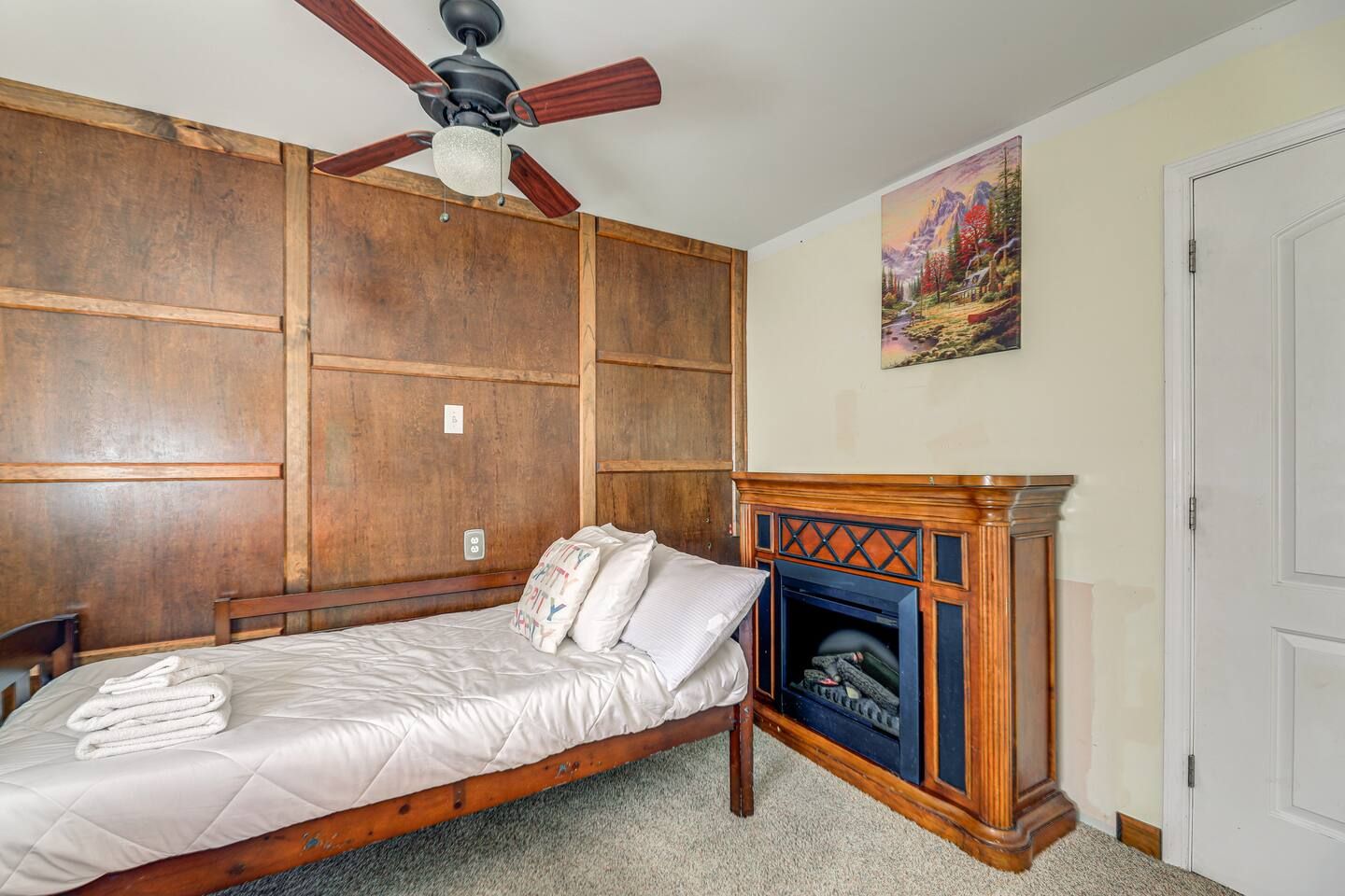Cozy bedroom with rustic wood accents and charming electric fireplace