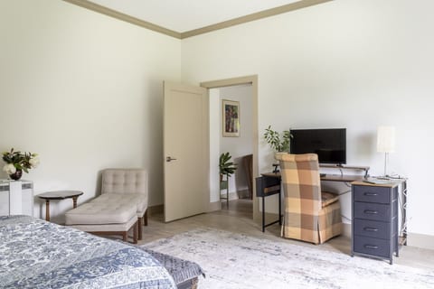 Bright, airy bedroom with workspace, TV, and cozy lounge seating
