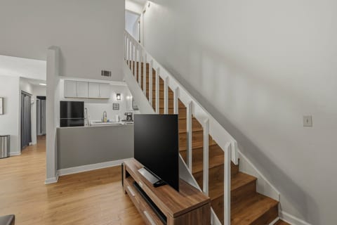 Bright open living space with wood floors, staircase, and modern kitchen