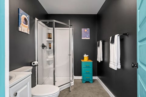 Modern black-and-white bathroom with glass shower and bold turquoise accents