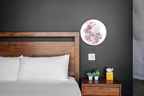 Cozy wood-accent bedroom with moon wall light and crisp white linens