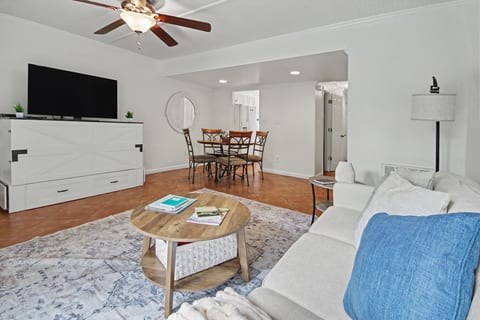 Bright open living room with dining area, big TV, and cozy seating