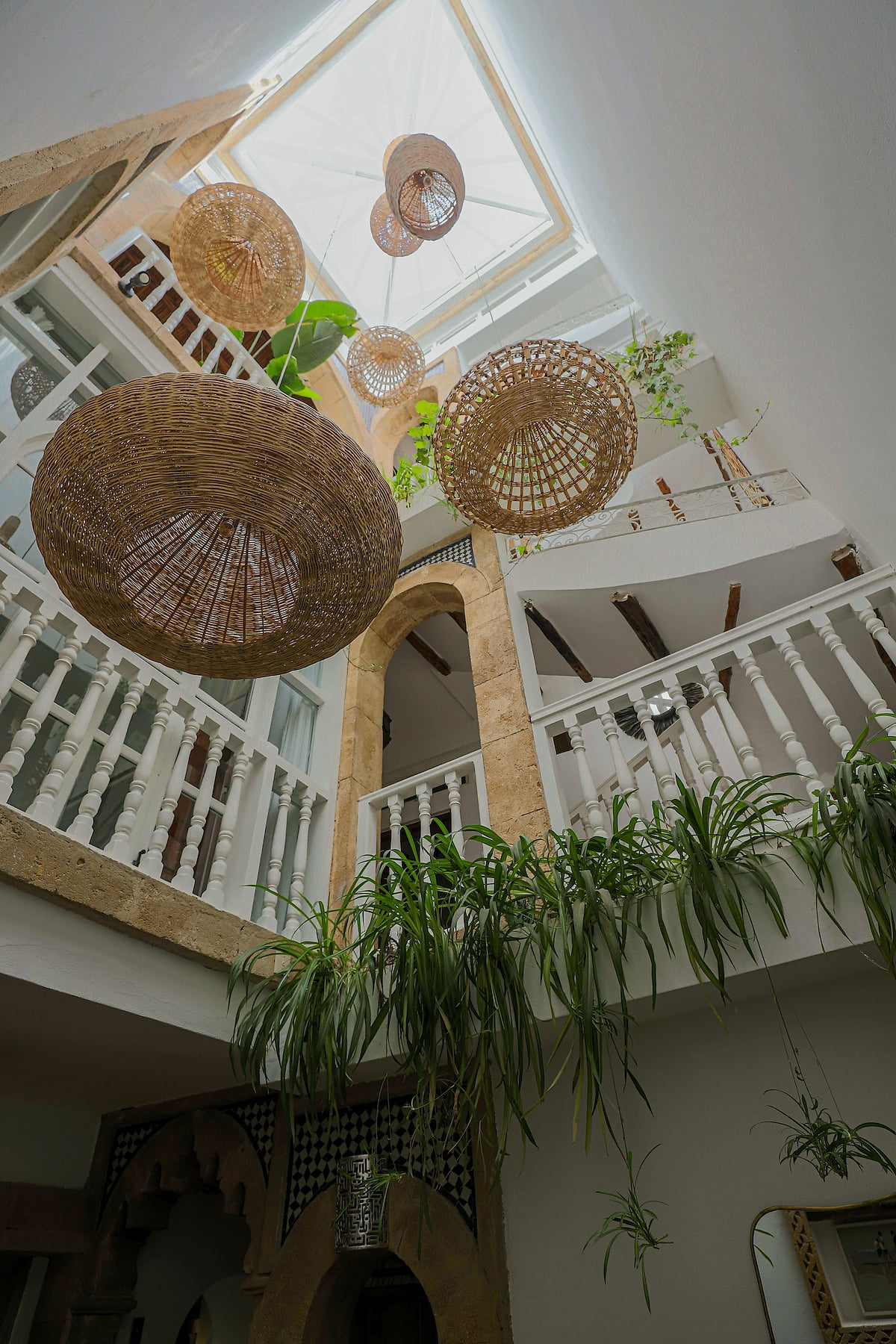 A bright patio with authentic Moroccan charm, featuring handcrafted pendant lights, lush greenery, and elegant architecture. Dar Mestoura · Bright Riad · Terraces with Sea View