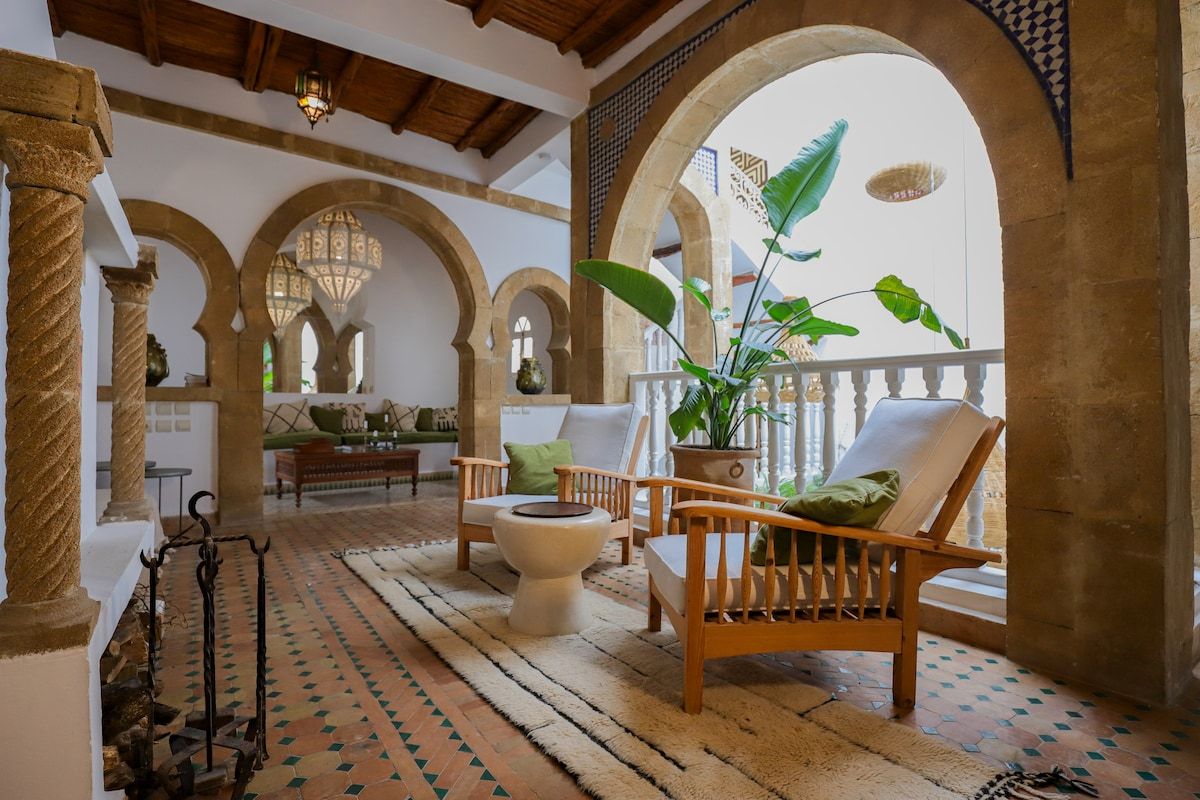 A bright living room with Moroccan arches, wooden furniture, and a soothing view of the terrace. A welcoming space that combines traditional charm with modern comfort.
