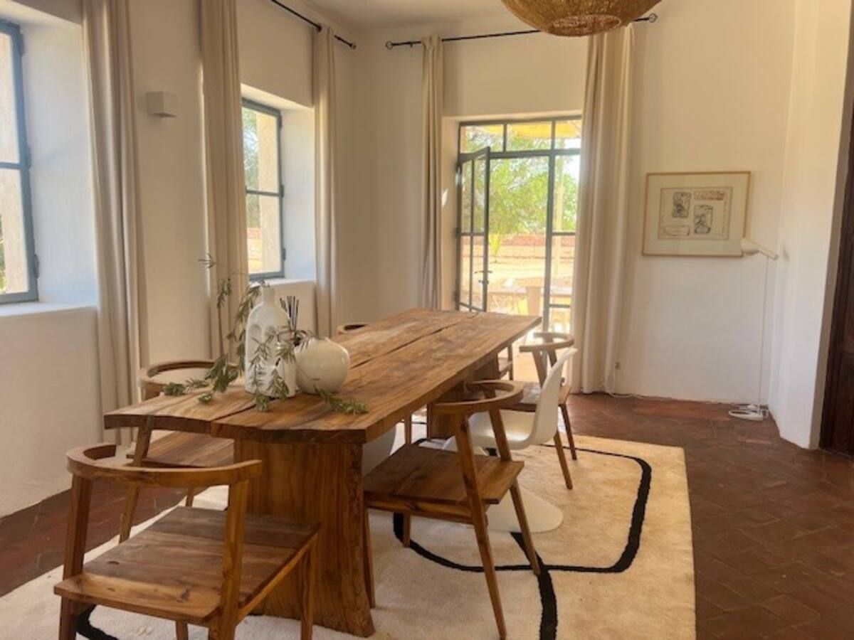Elegant and bright dining room with a large solid wood table. Ideal for sharing convivial moments, it offers a warm atmosphere and a beautiful view of the outdoors. Dar Sukun - Private haven 20 mn of Essaouira