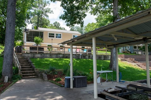 View from dock with boat house, electric boat lift, fish cleaning table and deck chairs. Water, retractable electric cord for onboard battery charging. Swim ladder, deep water and boat cleats with dockside fenders..