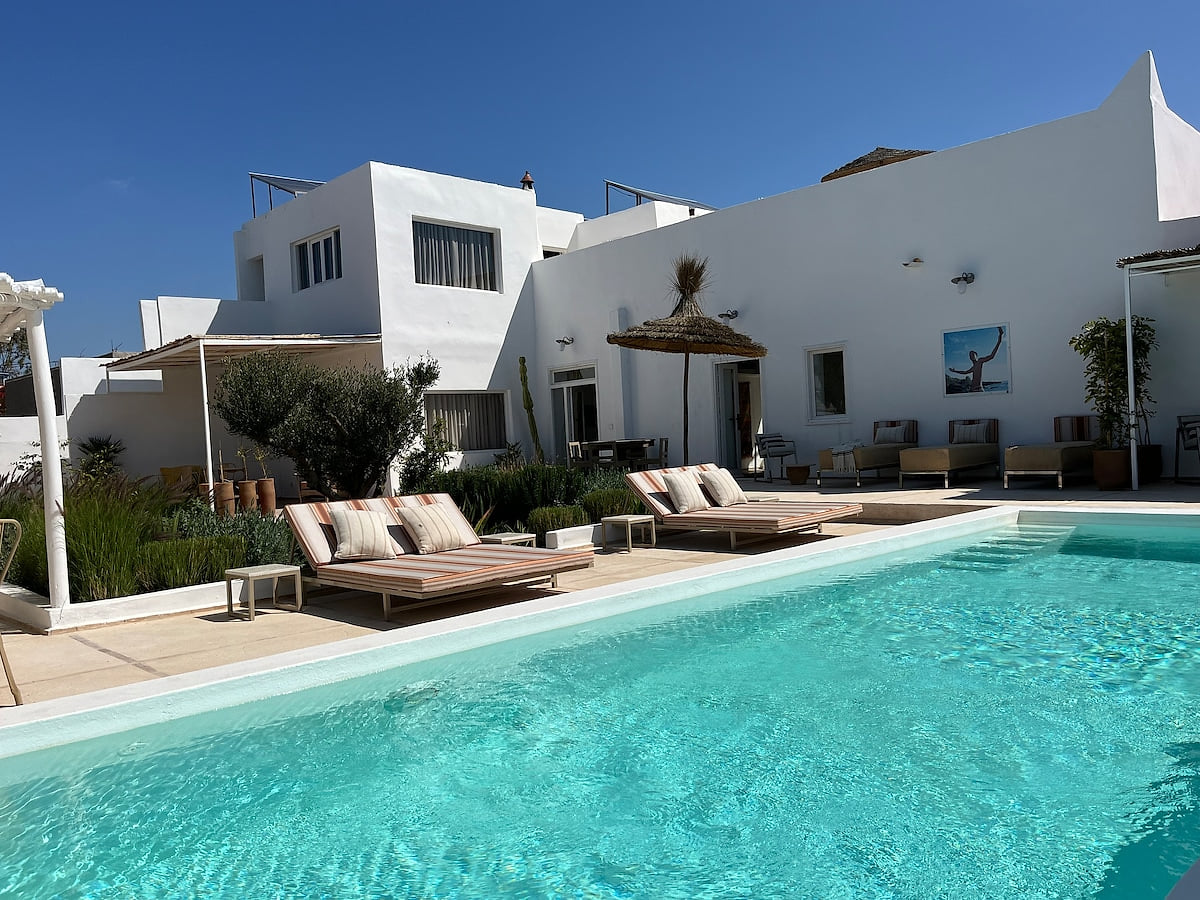 Elegant swimming pool with crystal-clear water and comfortable lounge chairs. A perfect spot to relax in the sun in a calm and elegant setting.