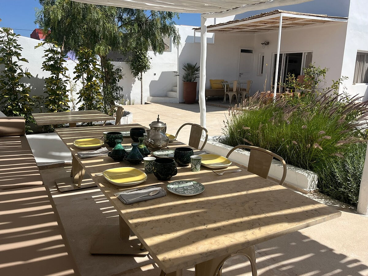 Cozy outdoor dining area under a pergola, perfect for enjoying time together outdoors in a warm and welcoming atmosphere. Dar Cocottes Chill · Pool Gardens