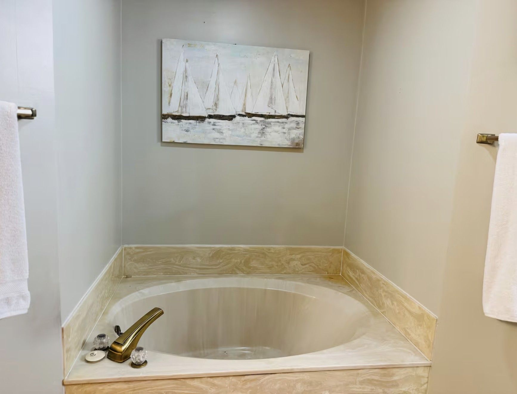 Relaxing soaking tub with elegant tile surround and calming coastal artwork