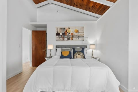 vaulted wood-beam ceiling, plush 14” mattress, modern decor, and warm natural light from two large windows. Features a big sliding mirror closet and an office desk for work or study.