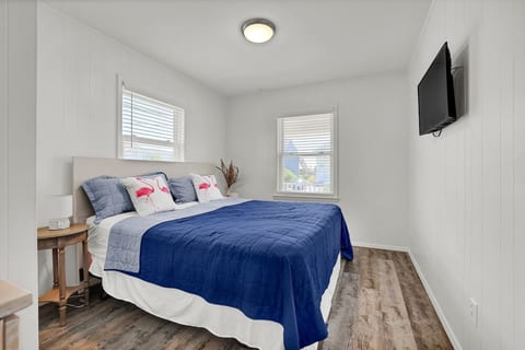 Bright, cozy bedroom with TV, natural light, and coastal touches
