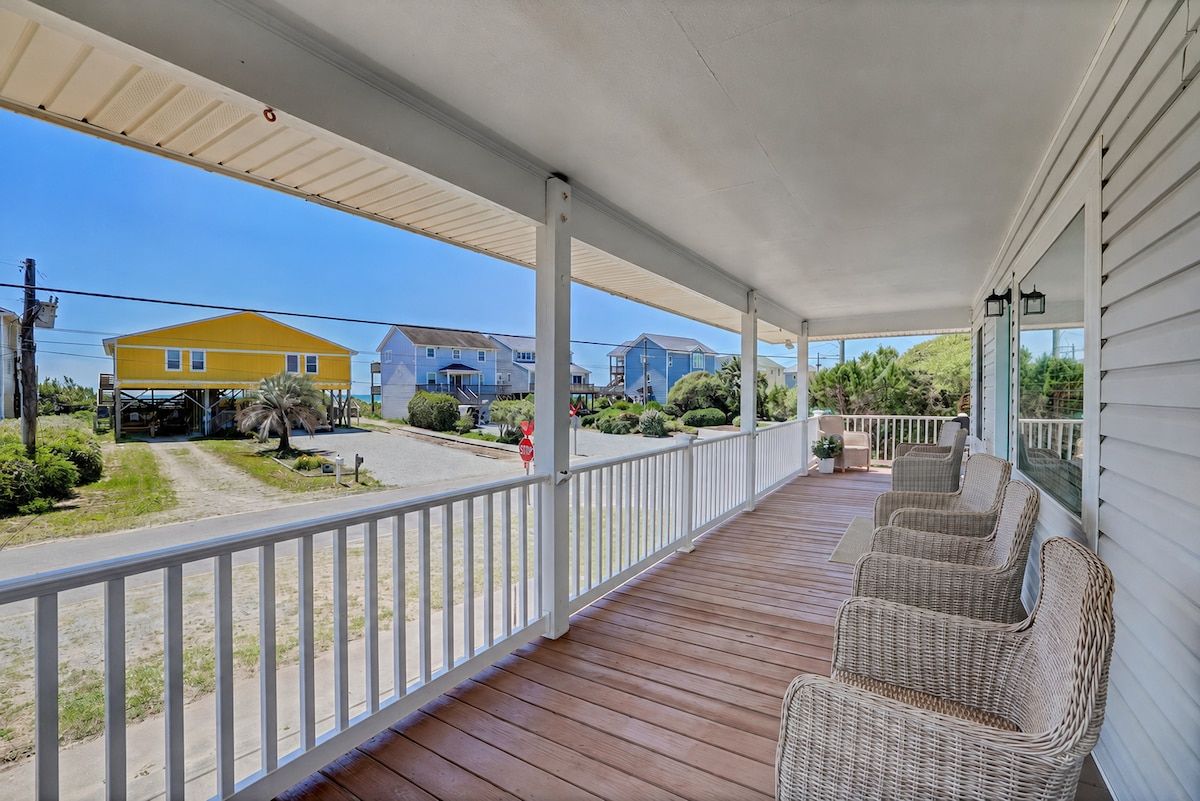 Spacious covered porch with wicker seating and sunny coastal views