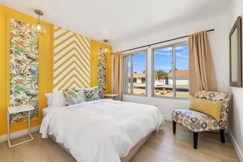 Cheerful bedroom w/ bold wallpaper, cozy bed, & sunny windows that set a fun, welcoming tone.