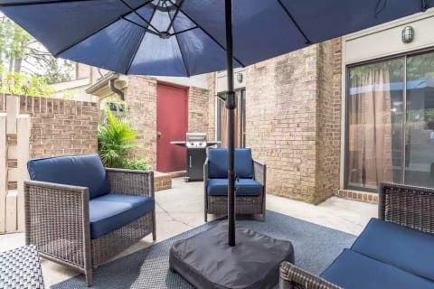 Attached private guest patio with large market umbrella shown open. Comfortable rocking wicker love seat and two wicker seats, small table, and a gas grill is provided to enjoy a nice Carolina day.