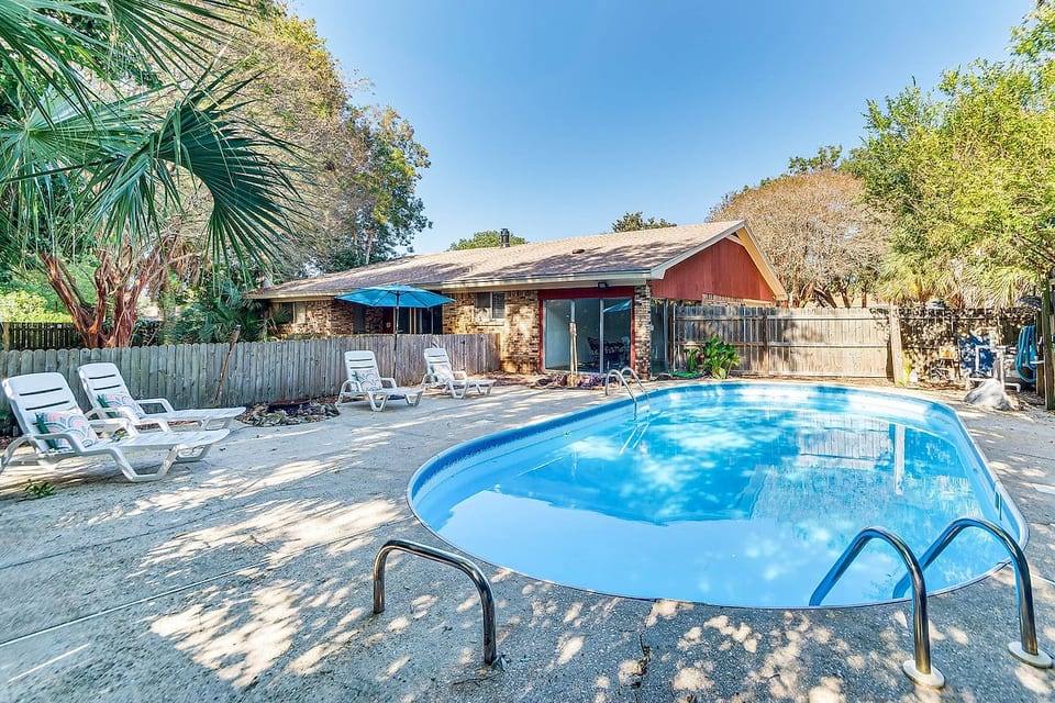 Sun-dappled palms frame your private pool oasis. Lounge poolside, dive into cool blue water, and gather under the umbrella for laughter-filled afternoons. This shaded backyard retreat is where family memories are made, one splash at a time.